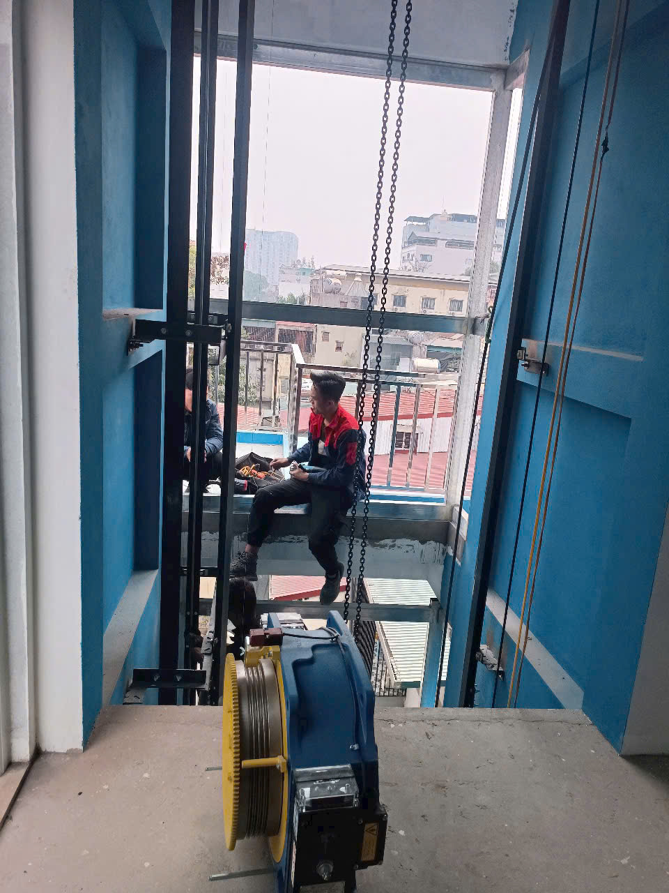 Thợ kỹ thuật đang lắp đặt máy kéo thang máy trong giếng thang của tòa nhà cao tầng